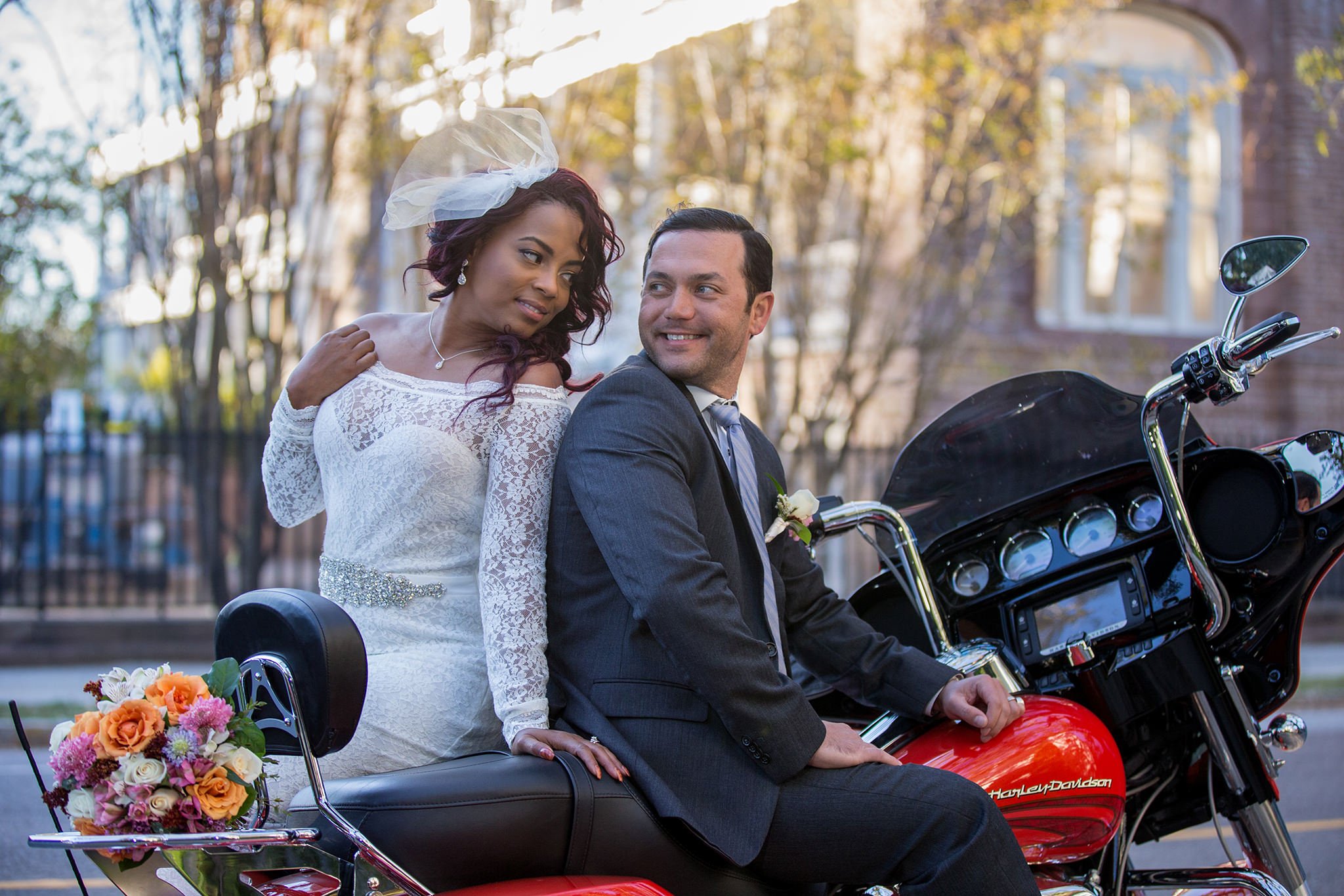 The couple is sitting on the ride motorbike, the bride and the groom are looking at each other