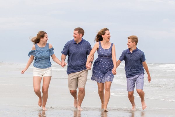 family photo charleston family is walking in the water holding hands
