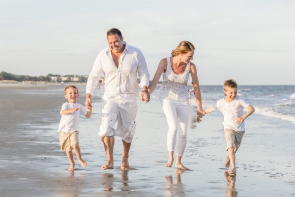 family photo charleston family is wearing white colors and walking on the beach 