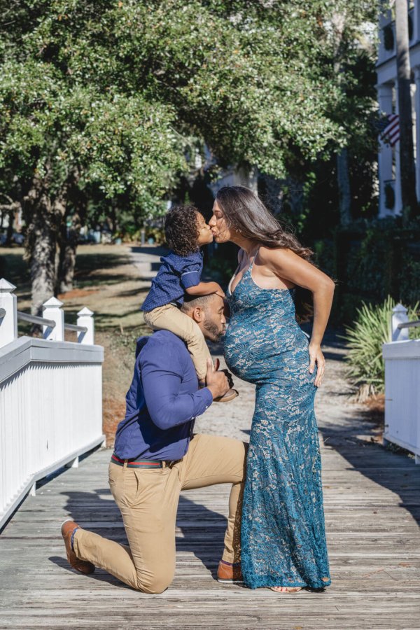 family photo charleston pregnant woman kisses her child while she is kissed by husband