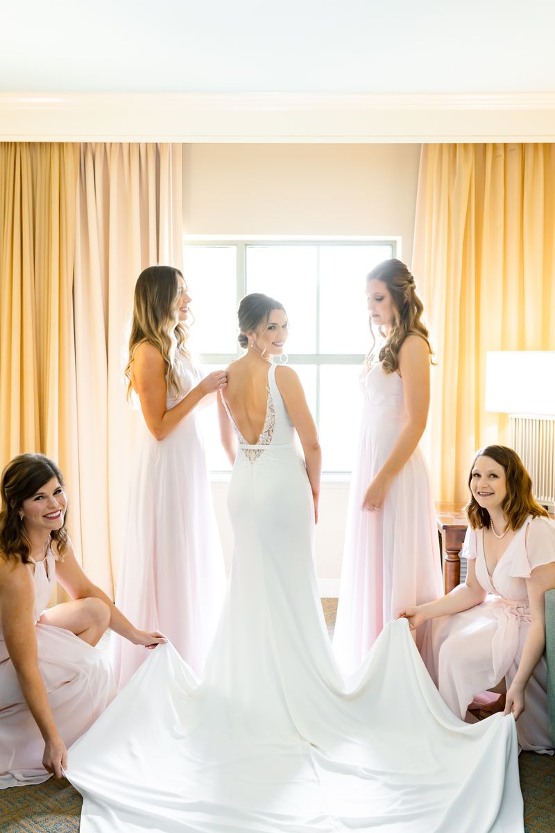 Bride getting ready with her bridesmaids adjusting her gown before a Charleston wedding