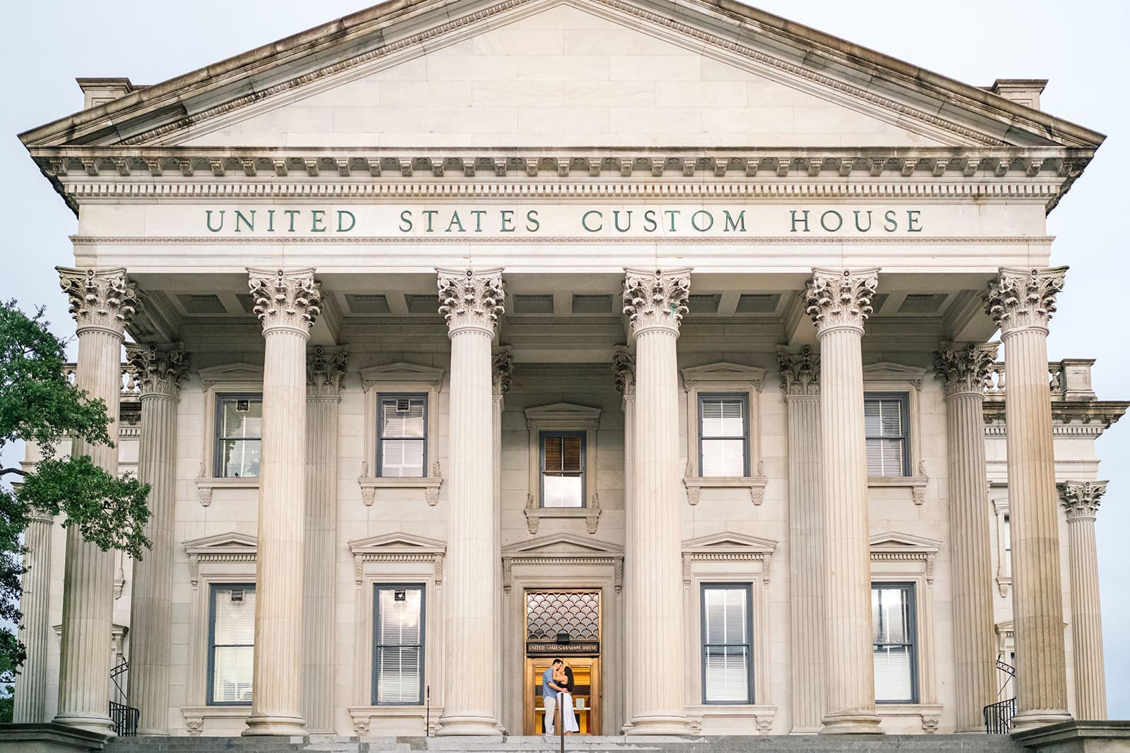 Couple kissing after proposal in front of the Charleston Custom House