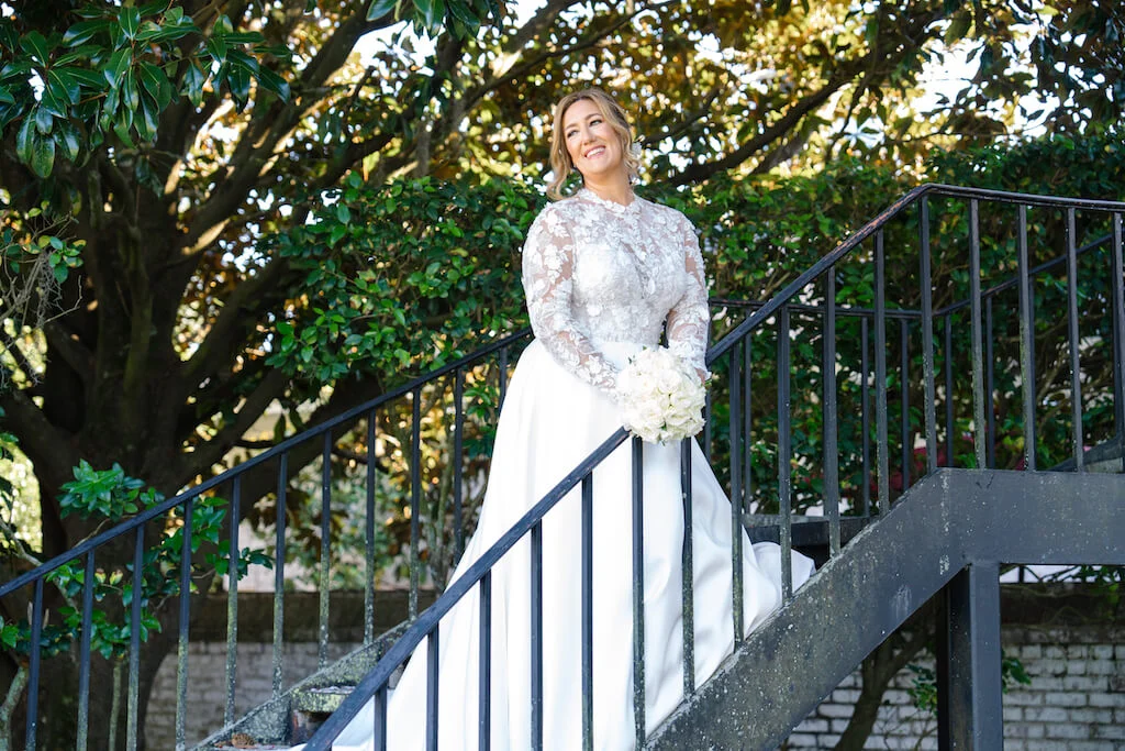 Bride in a long-sleeve lace gown on a staircase beneath the oaks — portrait by Jennifer, Charleston Photo Art